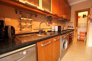 A modern kitchen with stainless steel appliances, wooden cabinets, and a built-in dishwasher. - Villa Salt, Sun, South (Vila Nova de Cacela)