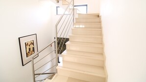 Eine Treppe mit Handlauf, ein gerahmtes Bild an der Wand und ein Fenster am Obergeschoss.