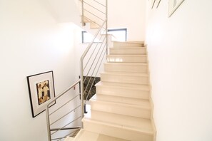 A staircase with a handrail, a framed picture on the wall, and a window at the top. - Villa Salt, Sun, South (Vila Nova de Cacela)