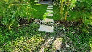 Un chemin mène à une maison moderne, entourée d’une végétation luxuriante et d’un jardin bien entretenu.