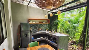 Une cuisine moderne dotée d’un îlot central intégré, d’un coin repas avec une table en bois et d’une vue sur un paysage verdoyant.