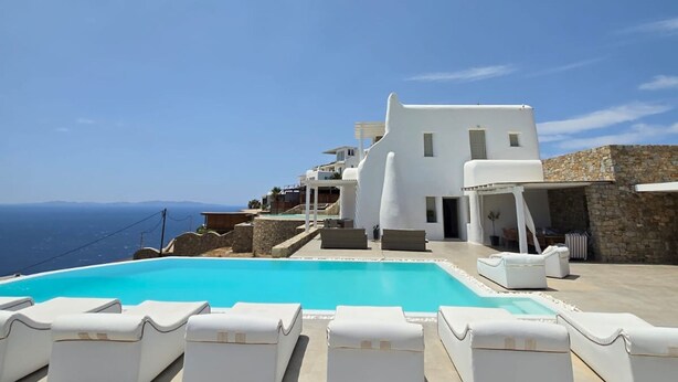 A white building with a pool and lounge chairs. - Atlas in Mykonos With 8 Bedrooms and 8 Bathrooms (Mykonos)