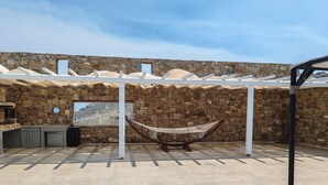 A stone-walled outdoor area with a hammock, a stone bench, and a pergola. - Atlas in Mykonos With 8 Bedrooms and 8 Bathrooms (Mykonos)