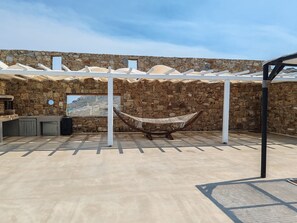 Ein Freibereich mit Steinmauern, einer Hängematte, einer Steinsitzbank und einer Pergola.