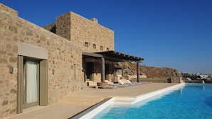 Un edificio de piedra con piscina, mobiliario exterior y vistas al paisaje.