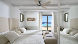 Habitación de hotel con dos camas, ventilador de techo, vista al mar y un radiador.