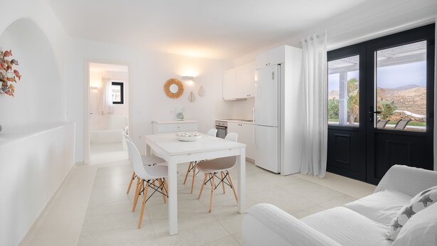 A modern, white-themed living room with a dining area, kitchen, and a balcony with a view. - Princess Estate in Mykonos (Mykonos)
