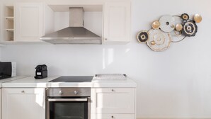 A kitchen with white cabinetry, a stainless steel range hood, and a built-in oven. - Princess Estate in Mykonos (Mykonos)
