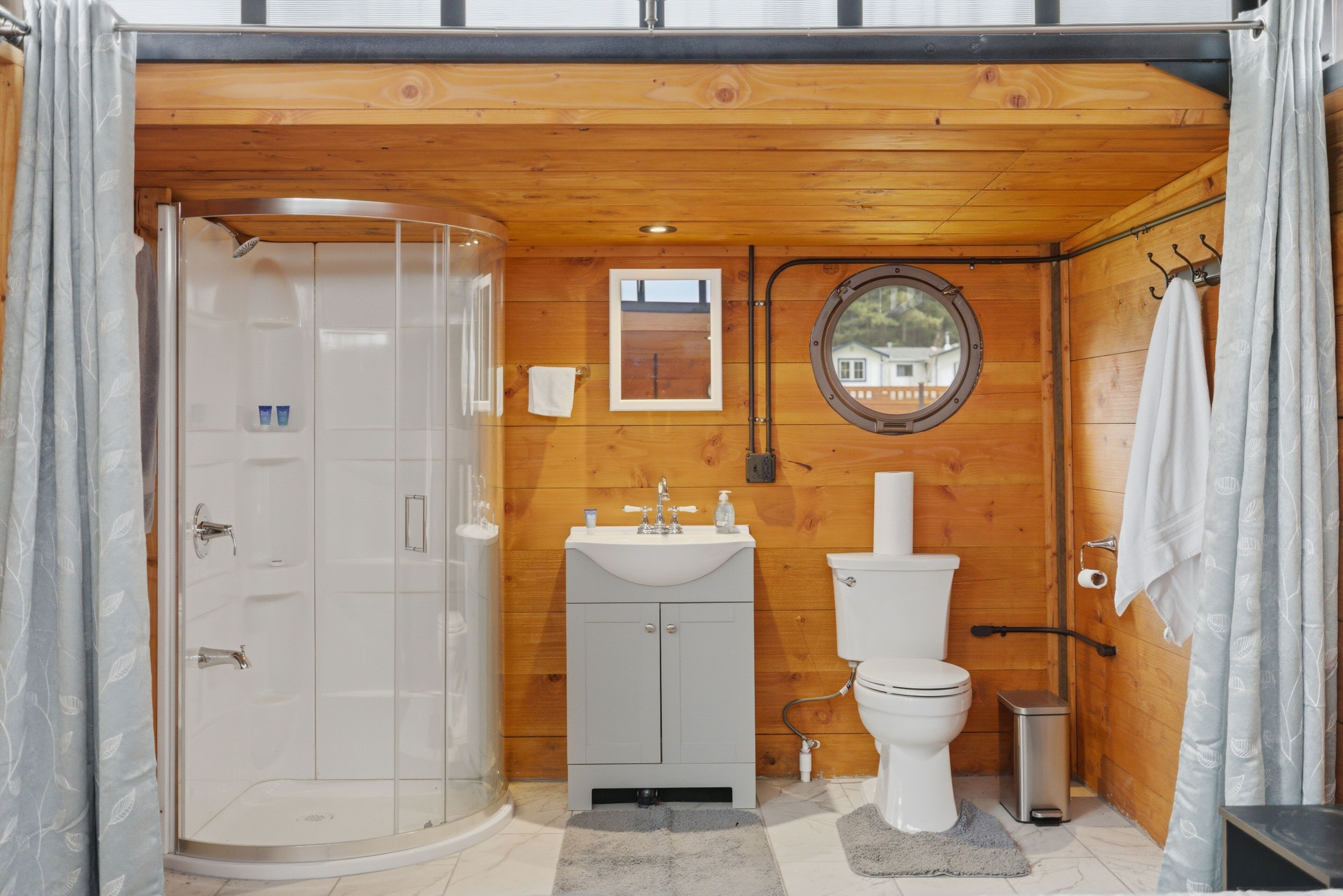 A bathroom with a shower, sink, toilet, and a mirror.