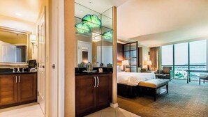A hotel room with a large bed, a sitting area, a dining table, and a view of the city. - MGM 11709 Deluxe Studio (Las Vegas)