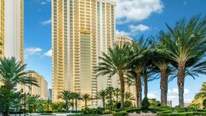 A high-rise hotel with a curved facade, surrounded by palm trees and a well-maintained garden. - MGM 11709 Deluxe Studio (Las Vegas)