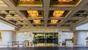 A hotel entrance with a modern design, featuring a glass door, a reception desk, and a ceiling with geometric patterns. - MGM 11709 Deluxe Studio (Las Vegas)