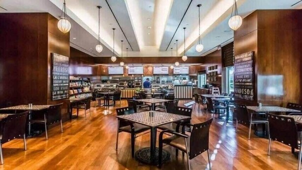 Un ristorante con pavimento in legno, tavoli, sedie e lampade a sospensione, con menù esposti.