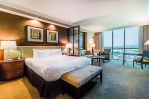 Ein Hotelzimmer mit einem großen Bett, einem Schreibtisch, einem Stuhl und Blick auf die Stadt.