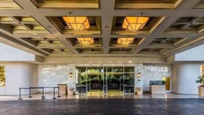 Ingresso di un hotel con facciata in vetro, una reception e un soffitto con illuminazione a incasso.