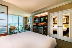 A hotel room with a large bed, a kitchenette, a dining area, and a view of the city. - MGM Sub Penthouse Mountain View 35606 (Las Vegas)