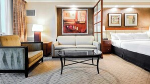 Ein Hotelzimmer mit einem Bett, einem Sofa, einem Sessel, einem Couchtisch und Bildern an den Wänden.