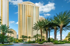 A tall, modern hotel with a curved facade, surrounded by palm trees and well-maintained landscaping. - MGM Signature 1BR with Balcony 08714 (Las Vegas)