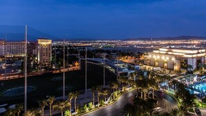 Un hôtel doté d’une piscine, d’un parking et offrant une vue sur le paysage urbain illuminé la nuit.
