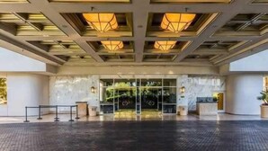 Ein Hotel mit modernem Design, das eine Glasfassade, eine Rezeption und eine strukturierte Decke zeigt.