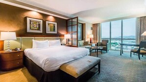 Ein Hotelzimmer mit einem großen Bett, einem Schreibtisch, einem Stuhl und Blick auf die Stadt.