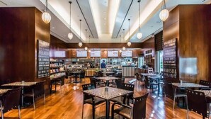 A restaurant with wooden flooring, tables with woven centerpieces, hanging pendant lights, and a bar area in the background. - Stunning MGM Studio Strip View 26611 (Las Vegas)