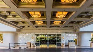 A hotel entrance with a modern design, featuring a glass door entrance, a reception desk, and a patterned ceiling with recessed lighting. - Stunning MGM Studio Strip View 26611 (Las Vegas)