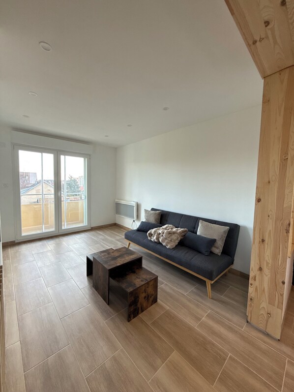 Un salon spacieux comprenant un canapé, une table basse et une porte-fenêtre coulissante donnant sur un balcon.