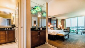 Ett hotellrum med en säng, ett skrivbord, en stol, ett stort fönster och utsikt över staden.