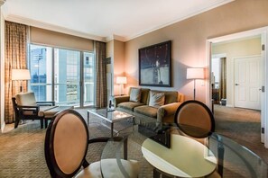 Ein Hotelzimmer mit großem Fenster, einer Couch, einem Couchtisch und einem Sessel.