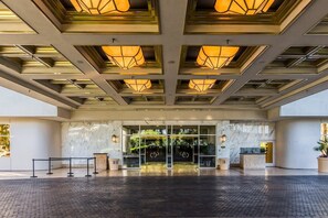 Ein Hotel mit Eingangsbereich, Glastür, Empfangsschalter und einem strukturierten Boden.