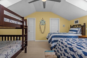 Ein Schlafzimmer mit Etagenbetten, einem Bett mit gestreifter Bettdecke und nautisch themenbezogener Wandgestaltung.