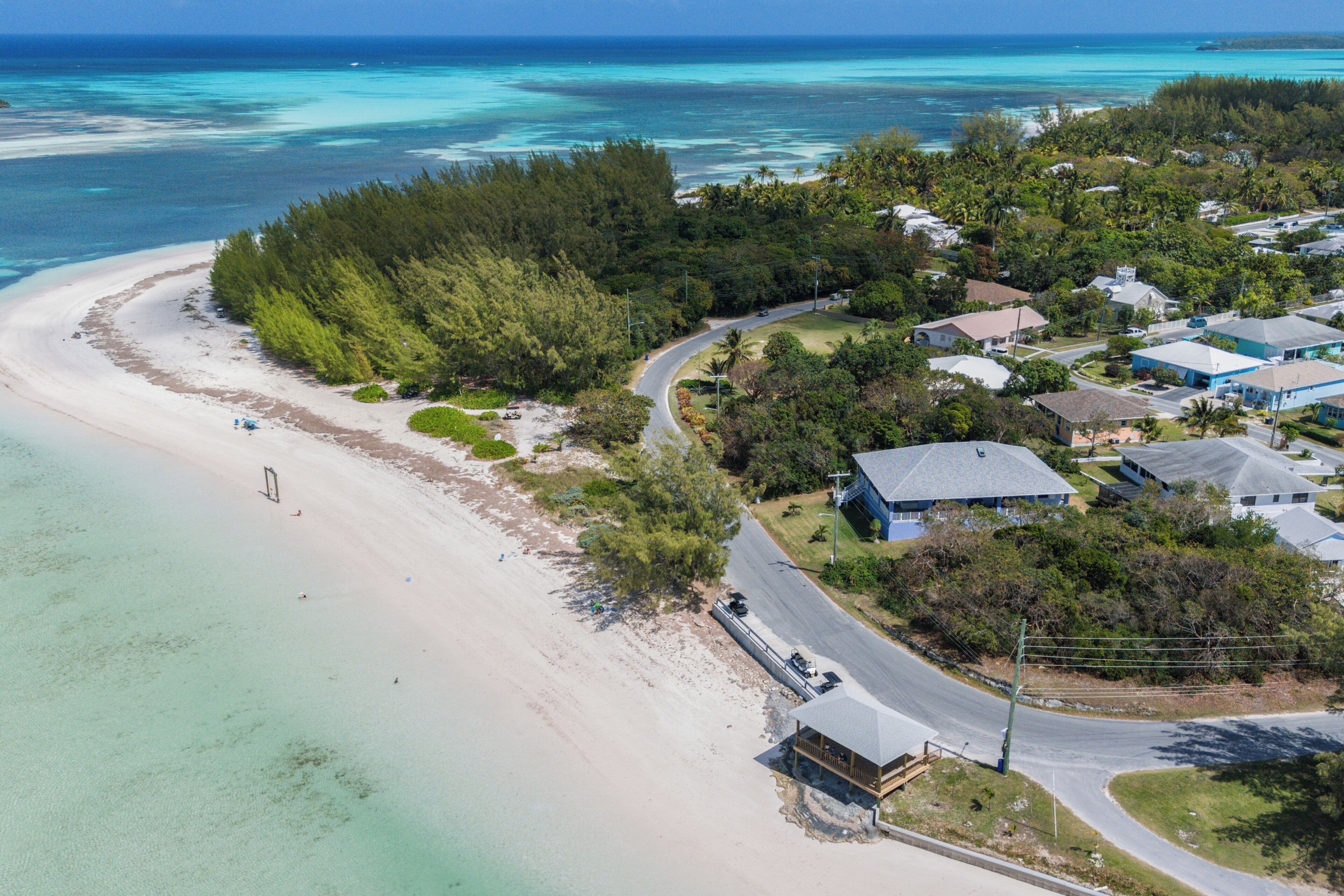 An aerial view of a coastal area with a beach, a road, and residential buildings.