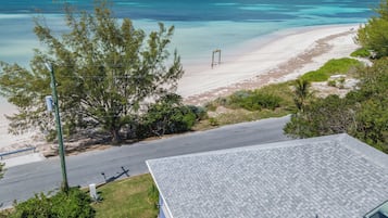 Vista de una playa con cielo despejado, orilla arenosa y vegetación.