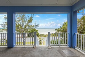 A covered porch with a view of the ocean and a parking area. - Family Friendly Pink Sand Beach House Sleeps 10 with Ocean Views (Spanish Wells)