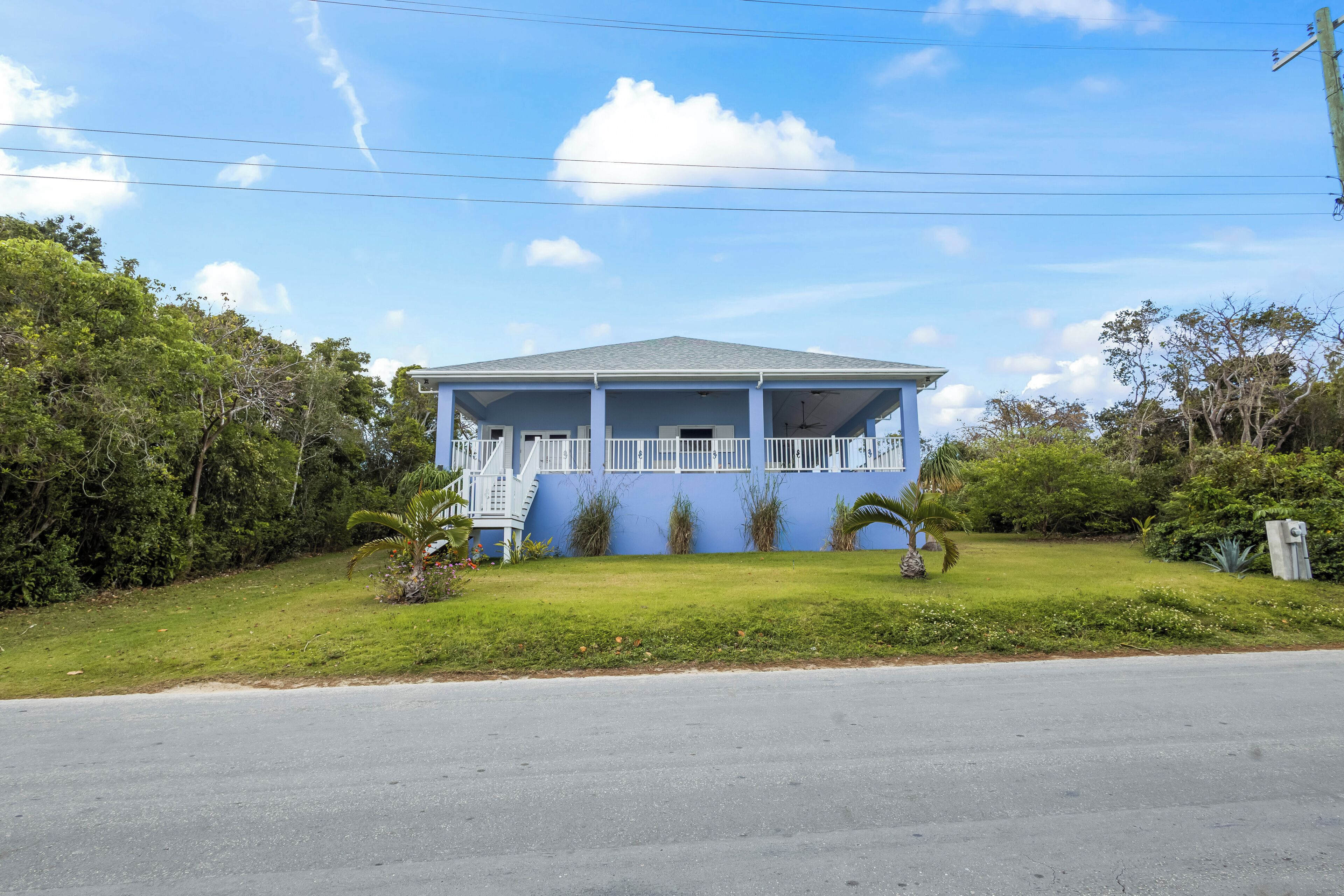 A single-story house with a blue exterior, a covered porch, and a small front yard.