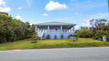 A single-story house with a blue exterior, a covered porch, and a small front yard.