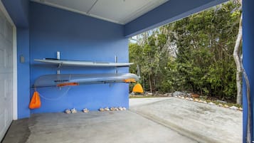Eine Garage mit zwei an der Wand befestigten Kajaks, einem Betonboden und Blick auf ein bewaldetes Gebiet.