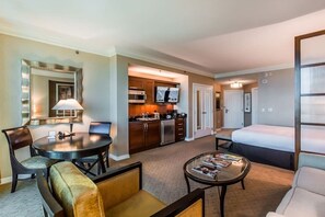 A hotel room with a dining table, a sofa, a coffee table, a TV, a kitchen area, and a bed. - Beautiful Studio Signature MGM Grand - No Resort Fees - Mountain View - Free Valet 2504 (Las Vegas)