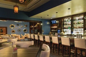 A bar area with multiple seating options, a bar counter, and a television screen. - Beautiful Studio Signature MGM Grand - No Resort Fees - Mountain View - Free Valet 2504 (Las Vegas)