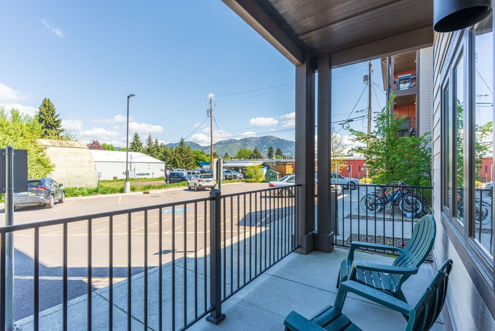 Un balcon avec vue sur un parking et les montagnes.