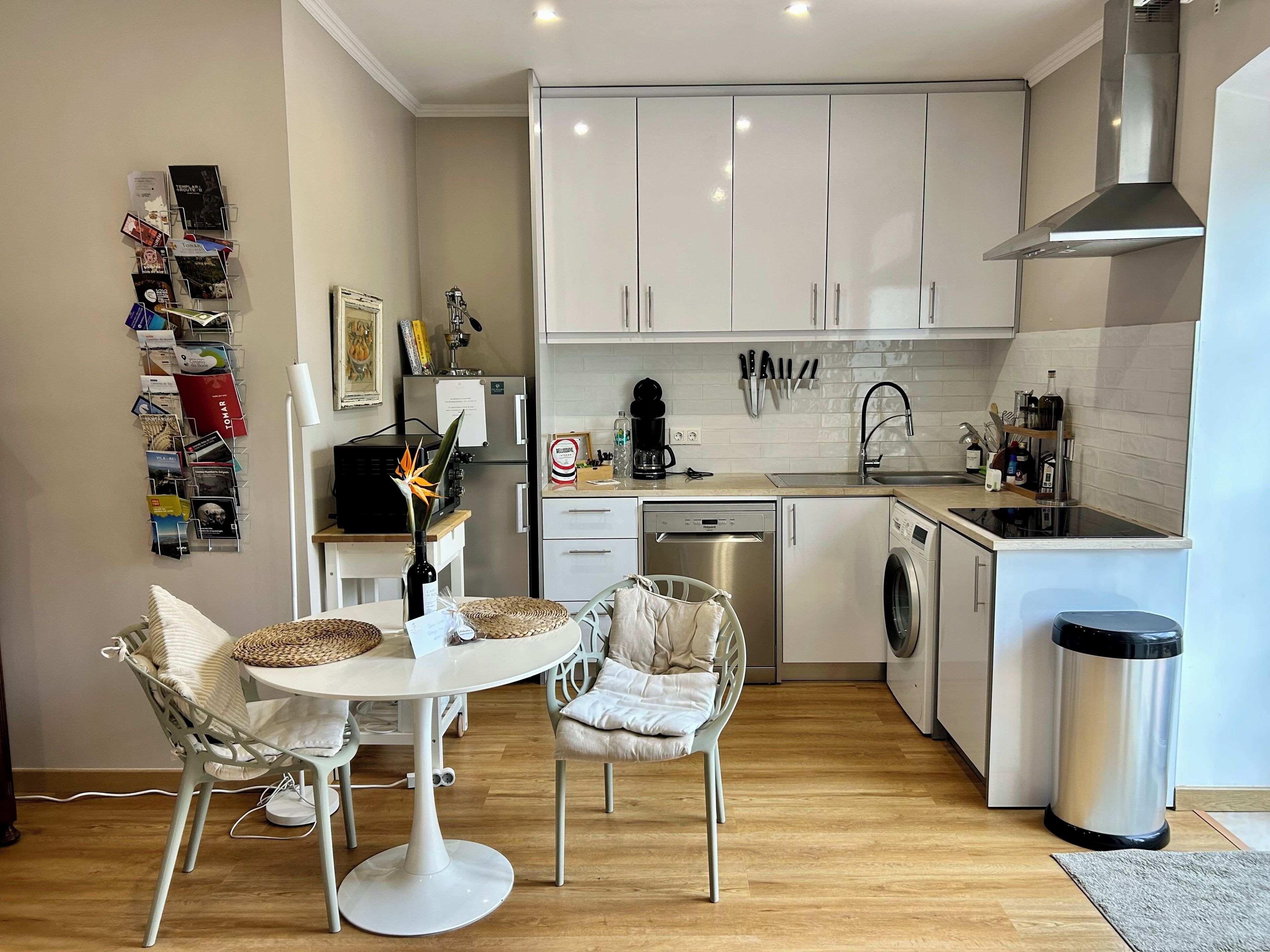 Una cocina moderna con armarios blancos, lavavajillas, lavadora y cafetera.