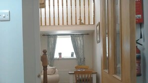 A narrow hallway leading to a room with a bed, a table, and a chair. - Cosy Cottage Retreat. Log Burner. Courtyard & Starry Skies (Consett)