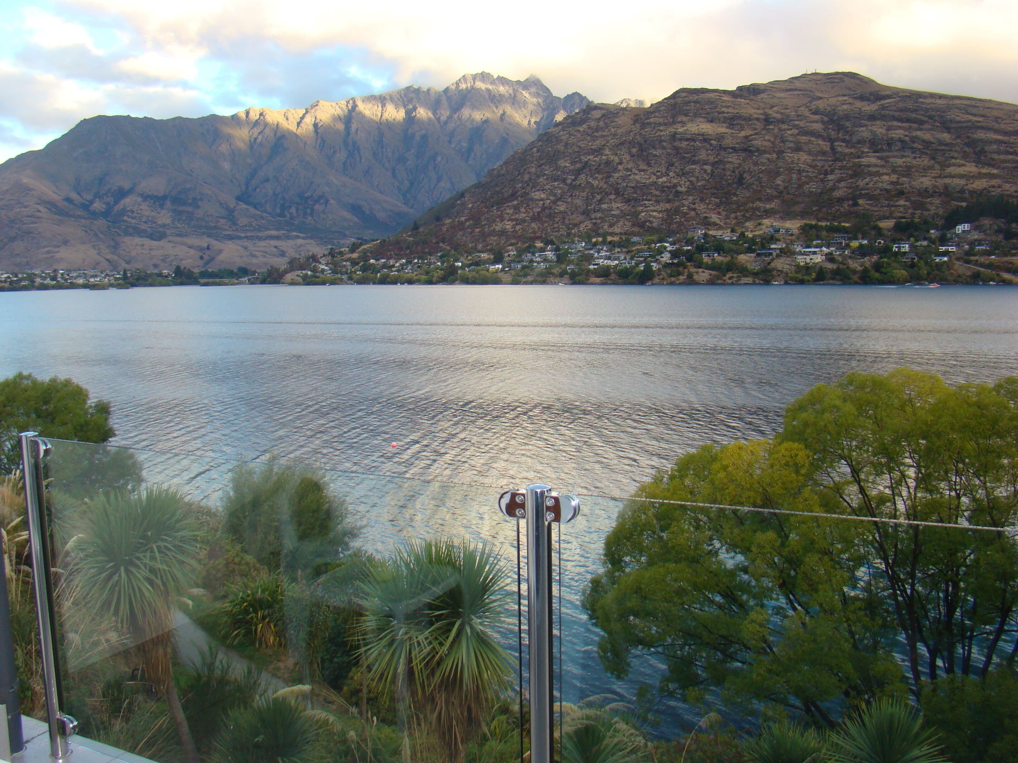 A lake with mountains in the background and a residential area along the shore.