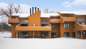 A multi-story wooden building with balconies, large windows, and a snow-covered roof. - Spacious 2 bdrm, 2 Bath with Loft, 1500 Sq Ft. Many onsite amenities with Golf/Skiing near by! (Harbor Springs)