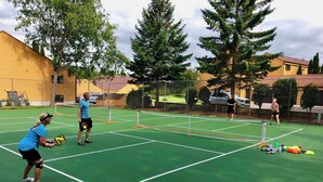 Een tennisbaan met een net, omringd door bomen en gebouwen.