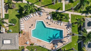 An aerial view of a swimming pool surrounded by lounge chairs and palm trees. - Enjoyable 1-bedroom 1-bath condo in charming Marco Island. (Marco Island)