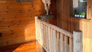 Un intérieur en bois, avec une rambarde en bois, une tête d’animal fixée au mur et un coin cuisine comprenant des placards et une cuisinière.