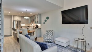 Un salon moderne avec un canapé, un fauteuil à motifs et un téléviseur fixé au mur.