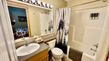 Une salle de bain avec un lavabo, des toilettes et une douche.